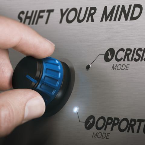 hand turning a dial to crisis mode 